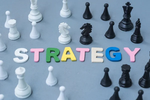 Wood text strategy with black and white chess around — Stock Photo, Image