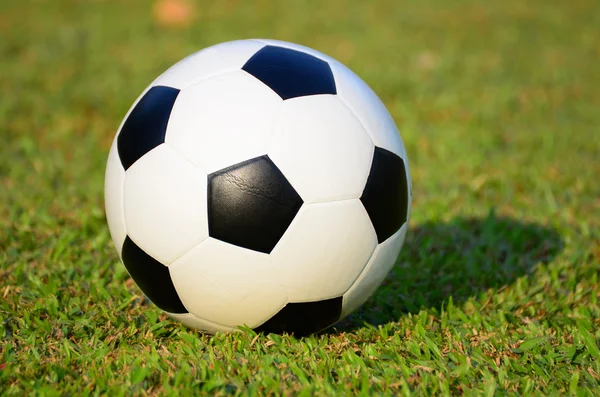 Football or soccer ball on green grass field — Stock Photo, Image