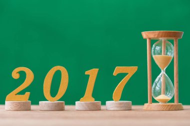 Altın ahşap yazı tipi yıl 2017 ve kum üzerinde ahşap masa saati