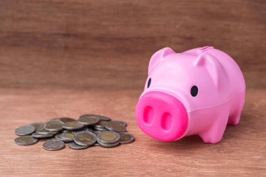 ahşap masa üzerinde paralar ile plastik pembe piggy banka