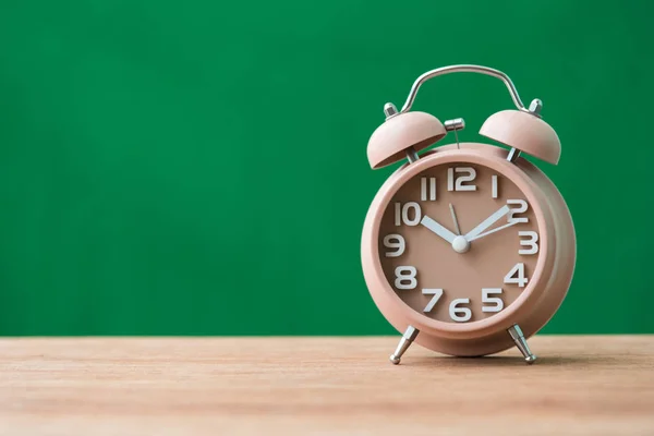 Alarmklocka på träbord med grön bakgrund — Stockfoto