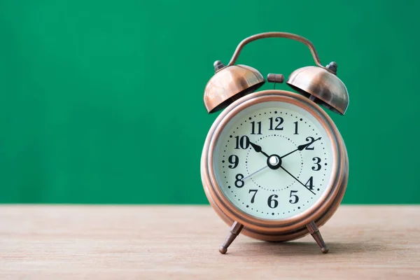 Alarmklocka på träbord med grön bakgrund — Stockfoto