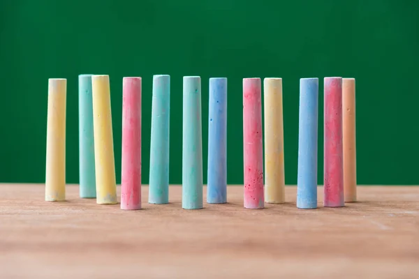 Tiza en una variedad de colores sobre la mesa con fondo verde — Foto de Stock