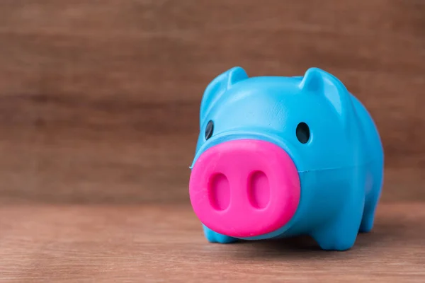 Banco piggy azul plástico na mesa de madeira — Fotografia de Stock