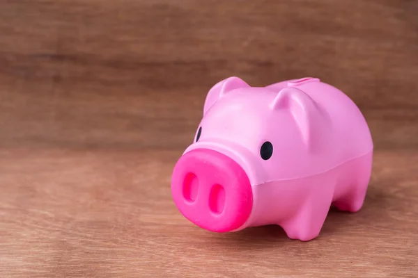 Plastic pink piggy bank on wooden table — Stock Photo, Image