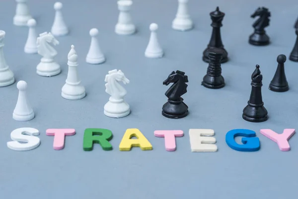 Wood text strategy with black and white chess around — Stock Photo, Image