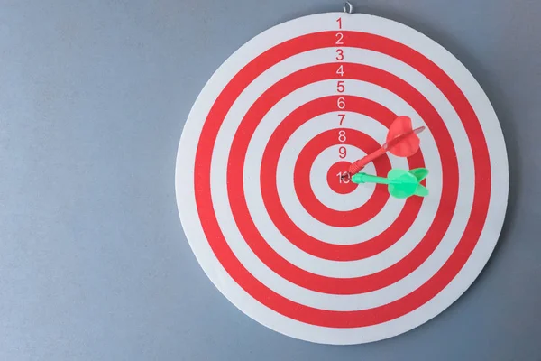 Red and green darts hit on centre of dartboard — Stock Photo, Image