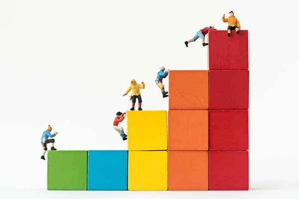 Scalatori in miniatura squadra arrampicata su pila di blocco cubo — Foto Stock