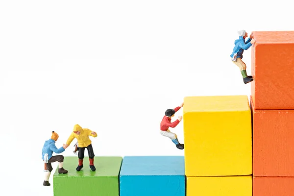 Miniatuur klimmers team klimmen op stapel kubus bouwsteen — Stockfoto