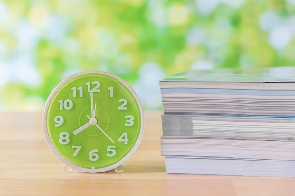 Grüne Uhr und Bücherstapel auf Holztisch — Stockfoto