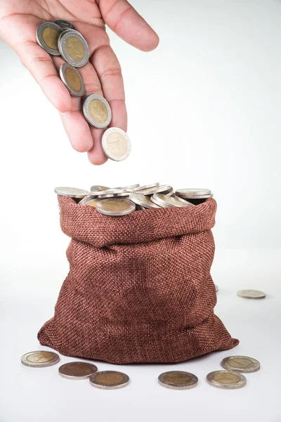 Монеты выплескиваются из рук человека в мешок с монетами — стоковое фото