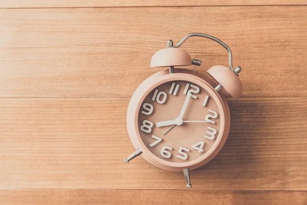 alarm clock on wood table , vintage tone