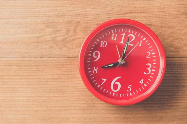 red clock on wood table , vintage tone