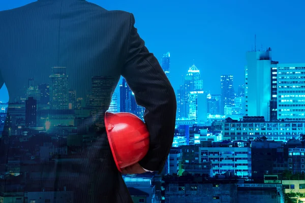business man in black suite holding red safety helmet