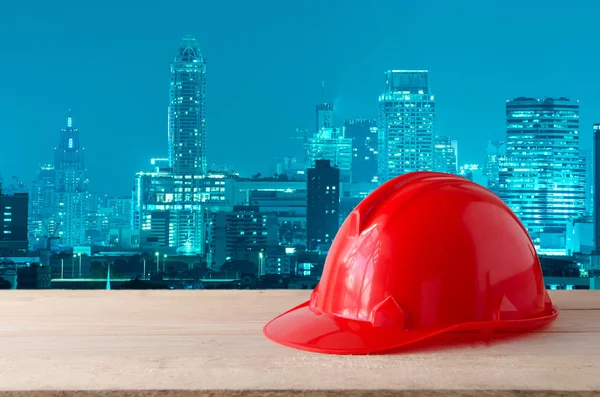 晚上现代城市建筑背景的红色安全头盔 — 图库照片