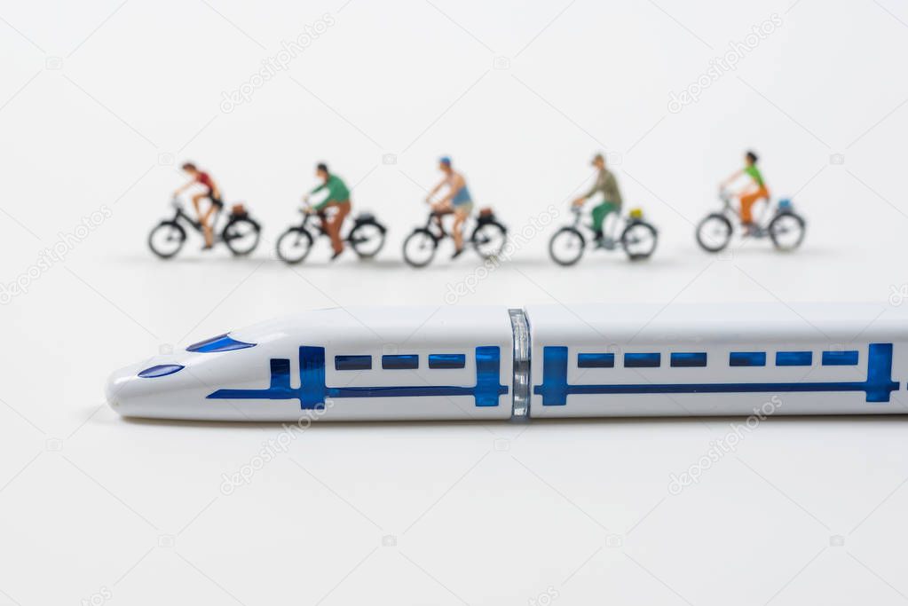 high speed train model and miniature people riding a bike