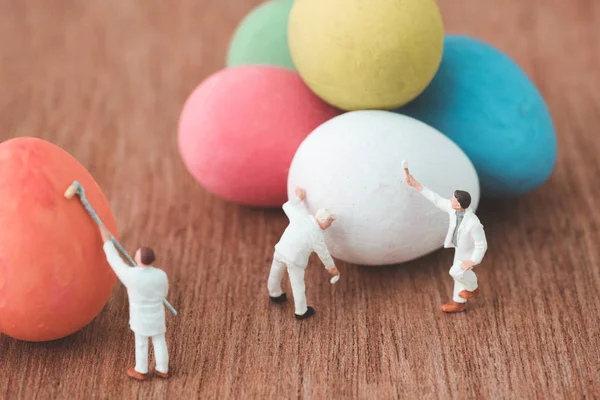 Pessoas em miniatura pintando ovos de Páscoa — Fotografia de Stock