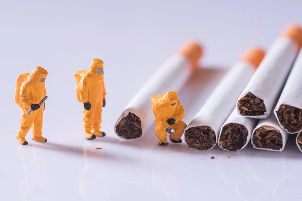 Miniature technician checking contaminants in cigarette — Stock Photo, Image