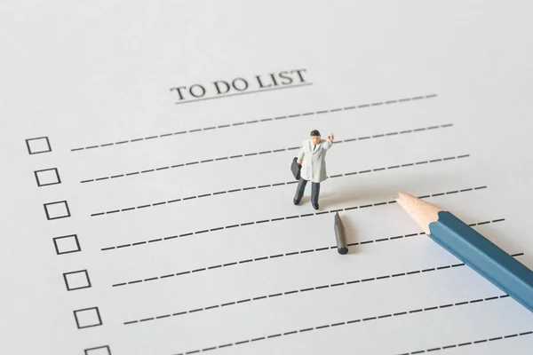 Business miniature figures people on to do list with a broken pe — Stock Photo, Image