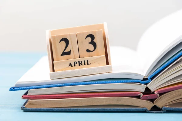 Calendario de madera para el 23 de abril en la pila de libros abiertos —  Fotos de Stock