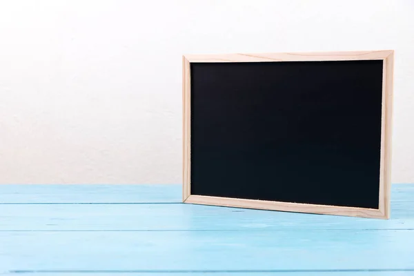 Small wooden black board on blue table — Stock Photo, Image