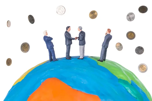 Personas en miniatura llegar a un acuerdo sobre el mundo y monedas cayendo — Foto de Stock