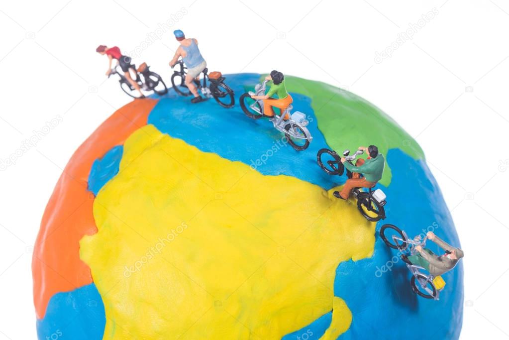 miniature people riding bicycle around the globe isolated on whi