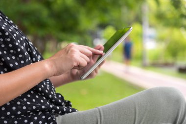Tablet kullanan kadın oturma whilte sakin ol yeşil park