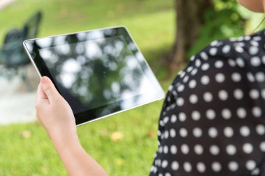 Tablet kullanan kadın oturma whilte sakin ol yeşil park