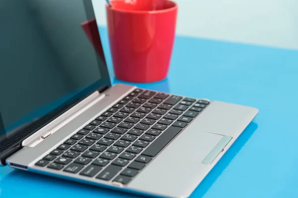 Laptop e xícara de café vermelho na mesa de trabalho — Fotografia de Stock