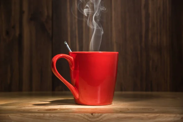 red coffee cup with smoke on wooden table background