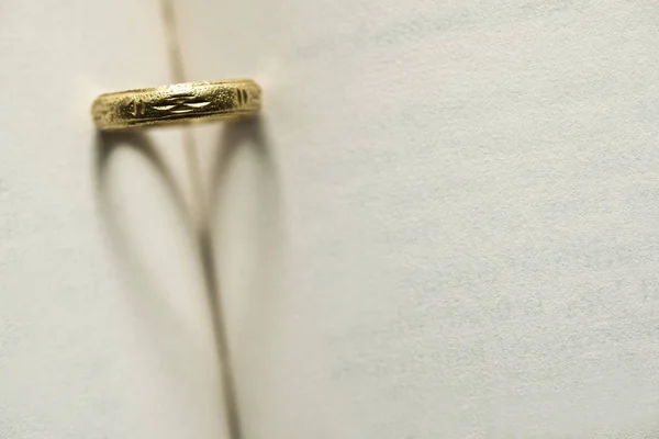 书页上的阴影的心形状的金戒指 — 图库照片