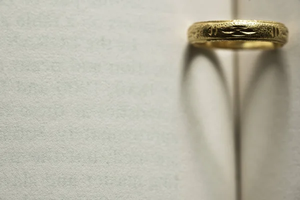 Anello in oro con ombra a forma di cuore sulla pagina del libro — Foto Stock