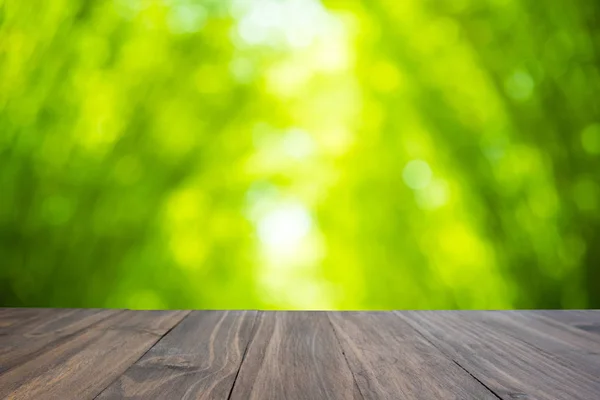 Braun Eichenholz Tisch auf abstrakten verschwimmen grünen Bambusblättern backgr — Stockfoto