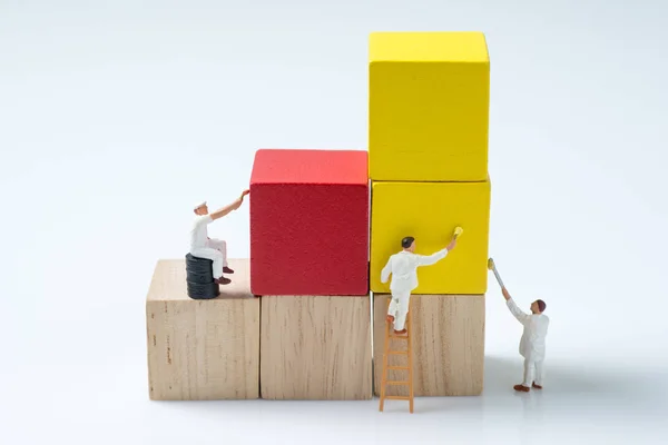 Pessoas miniatura trabalhador pintura cubo de madeira bloco de construção — Fotografia de Stock
