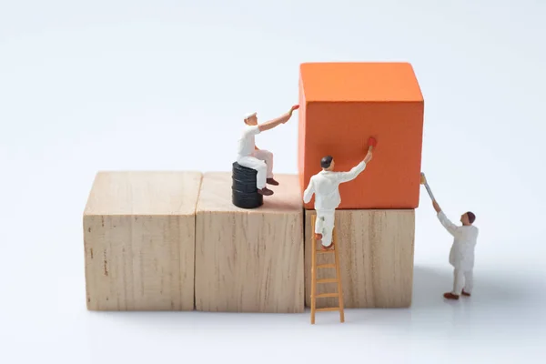 Pessoas miniatura trabalhador pintura cubo de madeira bloco de construção — Fotografia de Stock