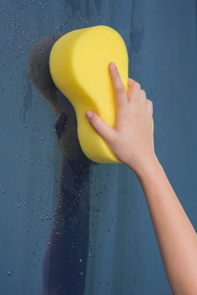 Γυναίκες χέρι χρησιμοποιώντας κίτρινο σφουγγάρι σκουπίστε τη γυάλινη — Φωτογραφία Αρχείου