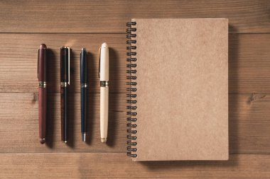 boş defter kalem üzerinde kahverengi ahşap masa ile