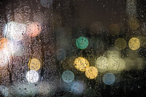 Natural water drops on glass window with night city bokeh backgr — Stock Photo, Image