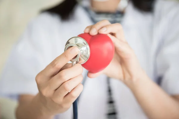 Profressional vrouw arts met groene stethoscoop controleren van rode h — Stockfoto