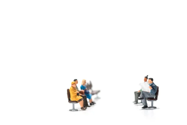 Fileiras de pessoas em miniatura figura sentado no banco backgroun branco — Fotografia de Stock