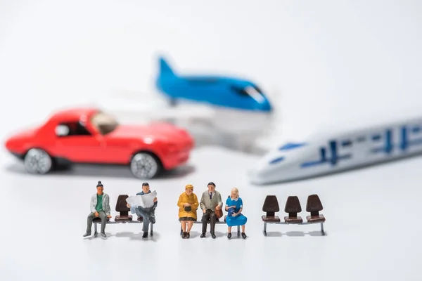 Fila di persone in miniatura figura seduta su panchina con aereo aereo, c — Foto Stock