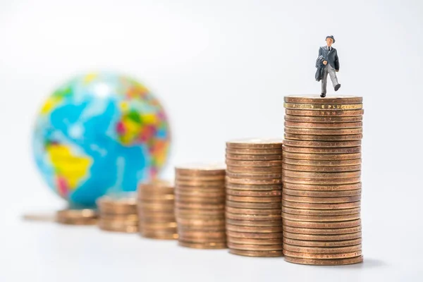 business miniature figure standing on stack of coins and globe f