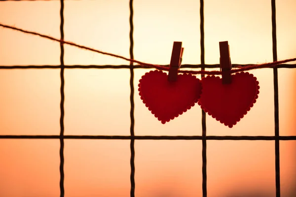Пара червоного серця висить на мотузці на сході сонця — стокове фото