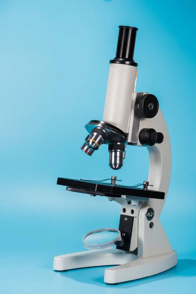 Microscópio de ciência em fundo azul claro — Fotografia de Stock