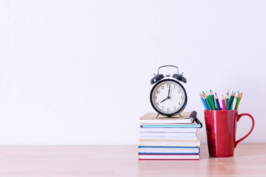 ahşap masa kitap yığını üzerinde kırmızı Kupası ve alram saat içinde kalem 