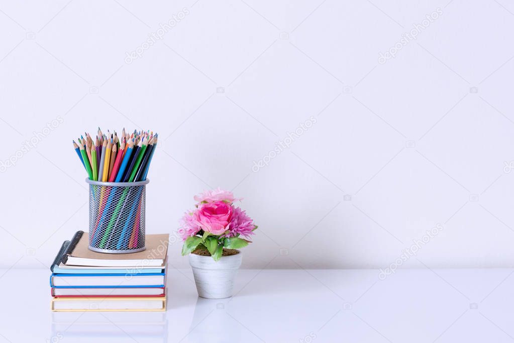 pencil box on book stack and artificial flower pot