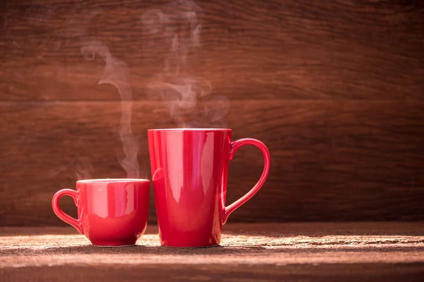 Xícara de café vermelho com fluxo de fumaça na mesa de madeira — Fotografia de Stock