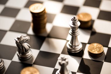 satranç taşları ve sikkeler üzerinde bir satranç tahtası yığını