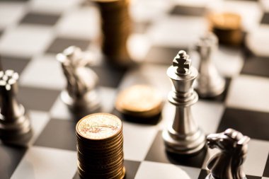 satranç taşları ve sikkeler üzerinde bir satranç tahtası yığını